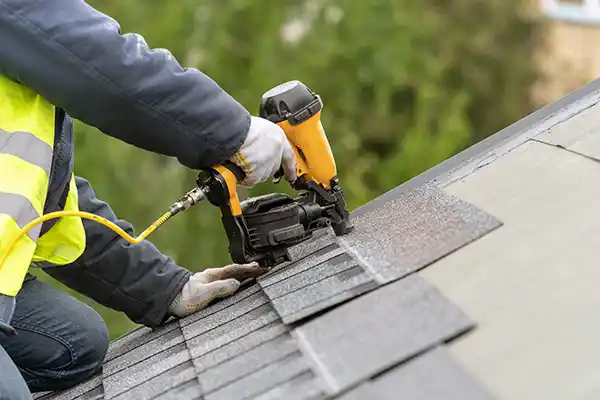 Roofer installing new gray shingles on a home